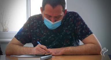 Na zdjęciu widać jedną osobę robiącą notatki
