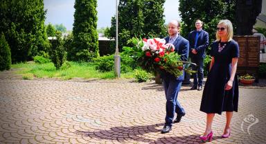 Na zdjęciu widać dwie osoby niosące kwiaty