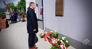 Na zdjęciu widać dwie osoby składające kwiaty