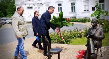 Na zdjęciu widać trzy osoby składające kwiaty
