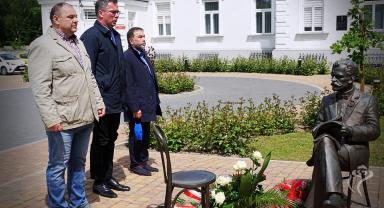 Na zdjęciu widać trzy osoby składające kwiaty