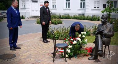 Na zdjęciu widać trzy osoby składające kwiaty