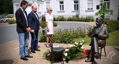 Na zdjęciu widać trzy osoby składające kwiaty