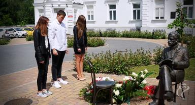Na zdjęciu widać trzy osoby składające kwiaty
