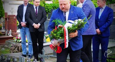 Na zdjęciu widać pięć osób, jedna składa kwiaty