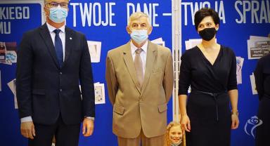 Na zdjęciu widać trzy stojące osoby
