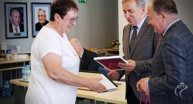 Na zdjęciu widać trzy osoby i moment wręczenia dyplomu