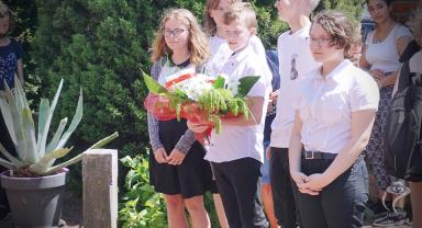 Na zdjęciu widać uczniów czekających na złożenie kwiatów
