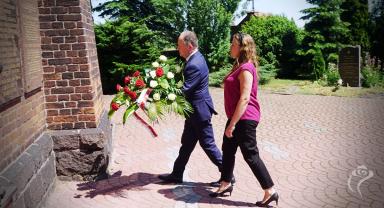 Na zdjęciu widać dwie osoby składające kwiaty