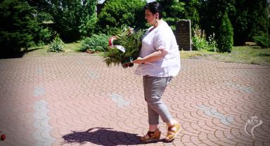 Na zdjęciu widać jedną osobę składającą kwiaty