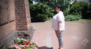 Na zdjęciu widać jedną osobę składającą kwiaty
