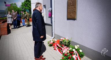 Na zdjęciu widać dwie osoby składające kwiaty