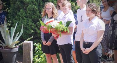 Na zdjęciu widać uczniów czekających na złożenie kwiatów