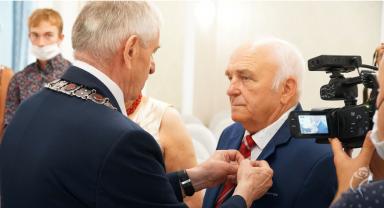 Na zdjęciu widać mężczyznę odznaczanego medalem przez prezydenta Kutna